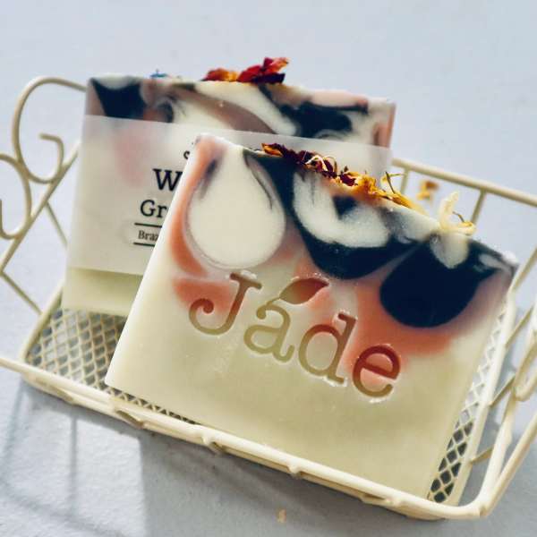Two decorative soap bars with pink and black swirls in a small cream metal basket