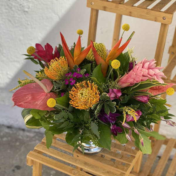 Tropical bouquet with pink, orange, and yellow flowers in a glass vase