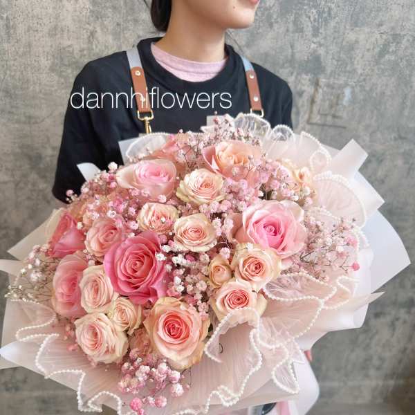 Large bouquet of pink and peach roses wrapped in pale pink paper