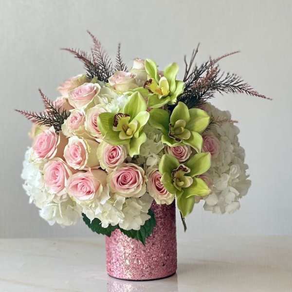 Pink roses and green orchids in a glittery pink vase