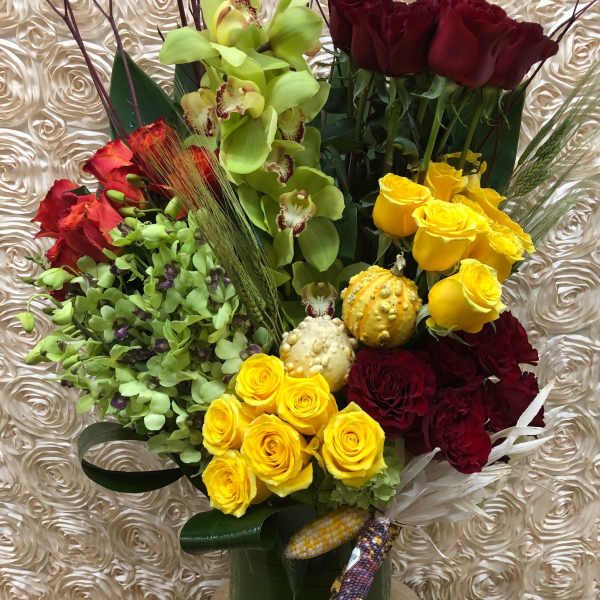 Mixed bouquet of roses and orchids in a tall green vase