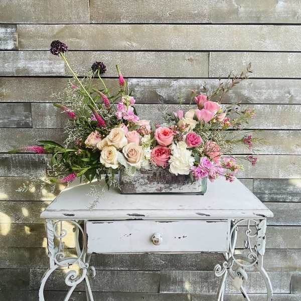 Pink and cream floral arrangement in a rectangular glass vase