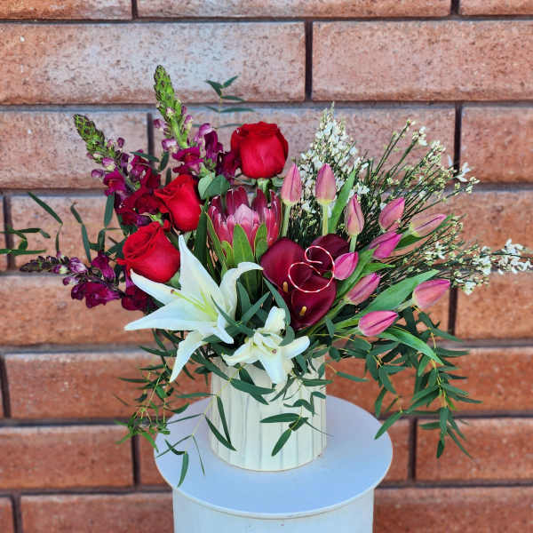 Bouquet of red roses, white lilies, and pink tulips in a white vase