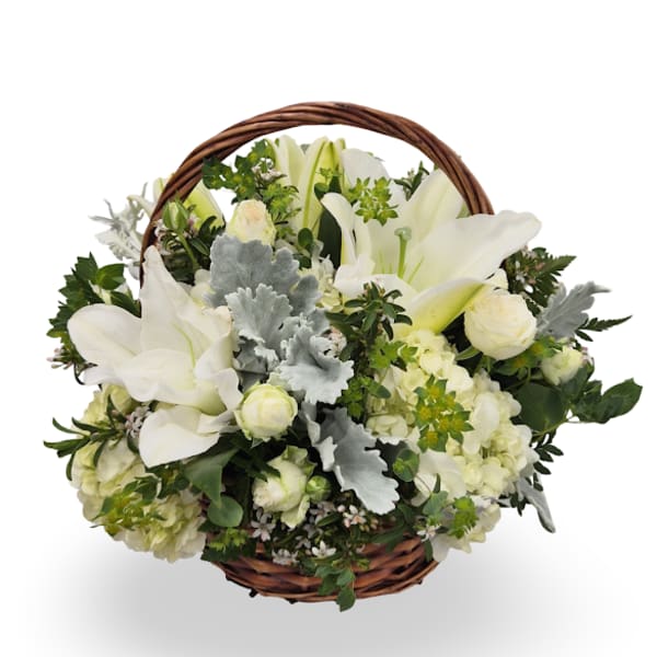 White lilies and roses arranged in a round wicker basket with handle