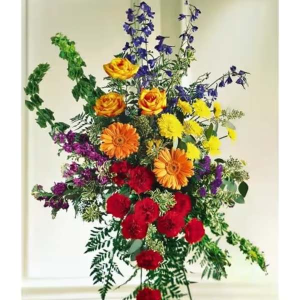 Tall standing spray on an easel with bright red, yellow, orange, and purple flowers.