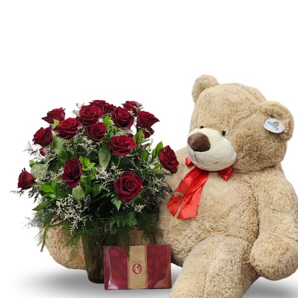 Red rose bouquet beside a large teddy bear with a red ribbon