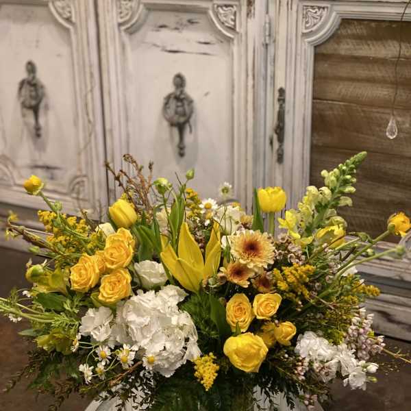 Yellow and white mixed flower arrangement in a clear glass vase