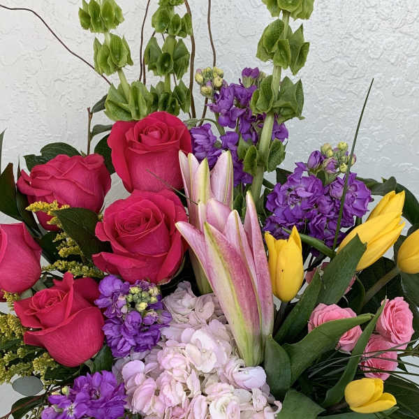 Mixed bouquet with hot pink roses, purple blooms, and yellow tulips