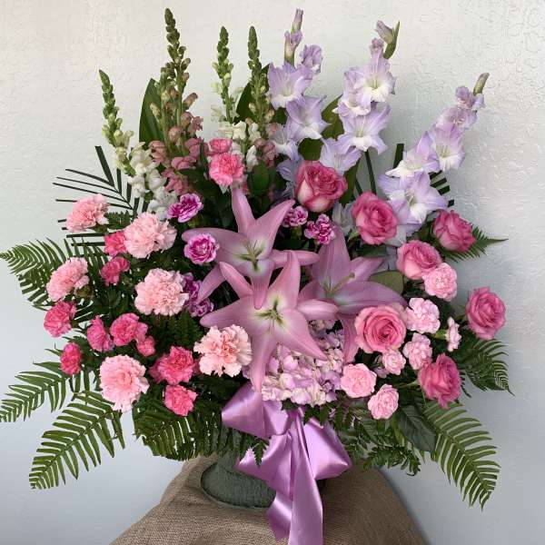 Pink and lavender floral arrangement with lilies, roses, and carnations in a vase