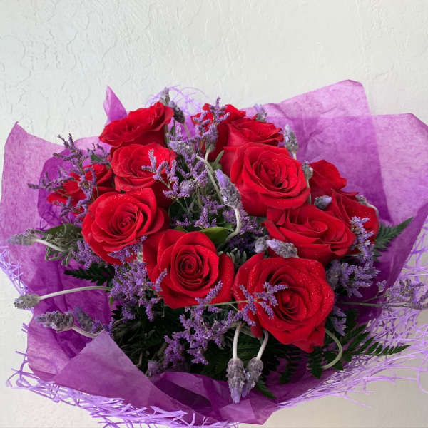 Bouquet of red roses with purple filler flowers wrapped in purple paper