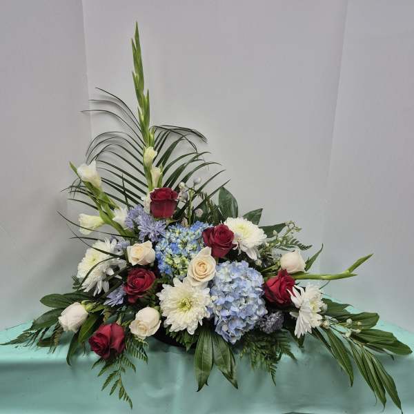 Low floral arrangement with roses, hydrangeas, and white blooms