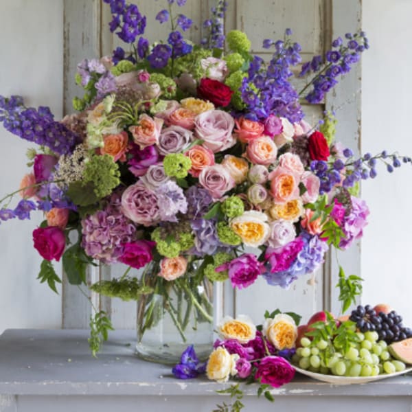 Large mixed bouquet of roses and purple flowers in a glass vase