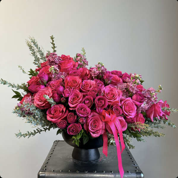 Pink rose bouquet in a black vase with ribbon