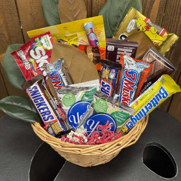 Basket of assorted candy bars with faux leaves behind it