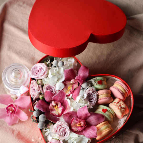 Heart-shaped red box with pink flowers and pastel macarons