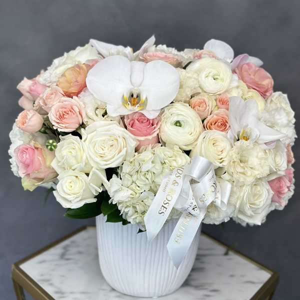 Pastel rose and orchid arrangement in a white vase