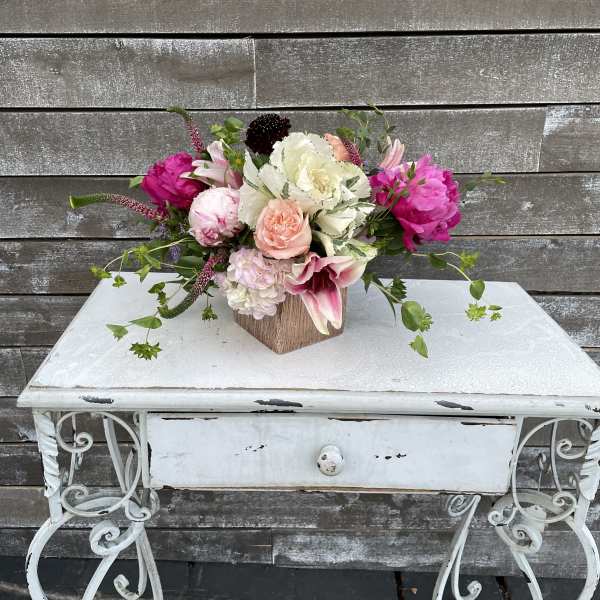 Mixed bouquet of pink, white, and peach flowers in a wooden cube vase