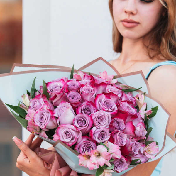 Large bouquet of pink and lavender roses with pink flowers in pastel wrapping