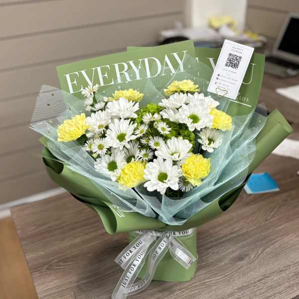 Bouquet of white daisies and yellow carnations wrapped in green paper