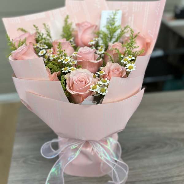 Pink rose bouquet with small white daisies wrapped in pale pink paper