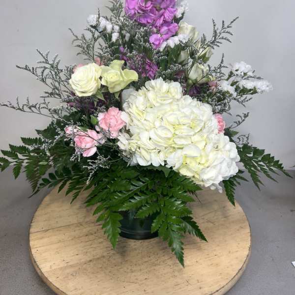 Tall floral arrangement with white and pink blooms in a dark vase