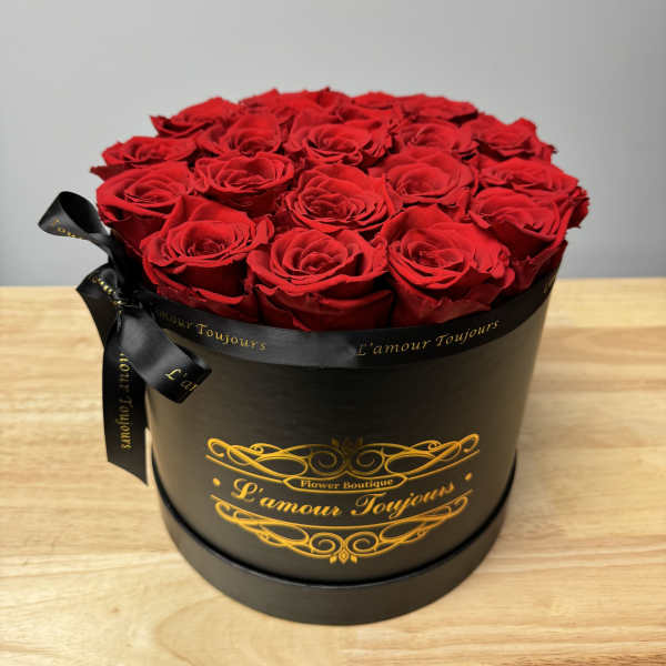 Round black hat box filled with tightly packed red roses