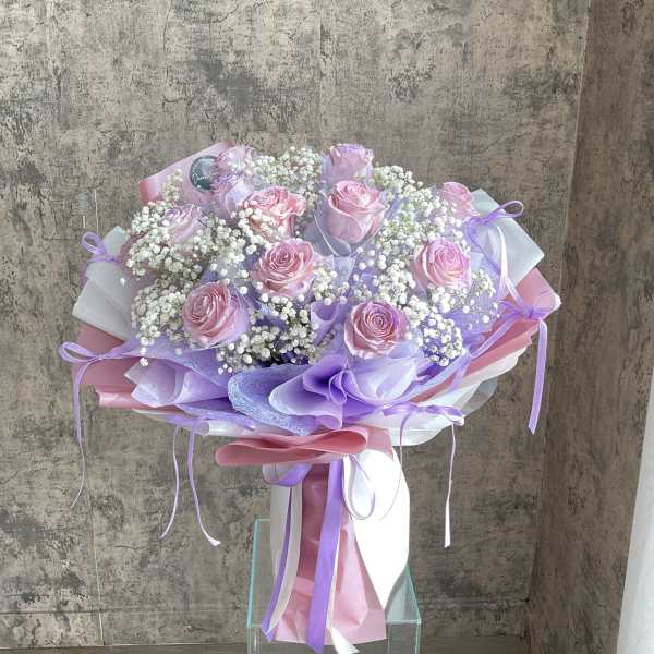 Bouquet of pink roses with white baby's breath and lavender wrapping