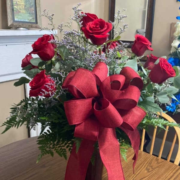 Red roses in a glass vase with a large red ribbon bow