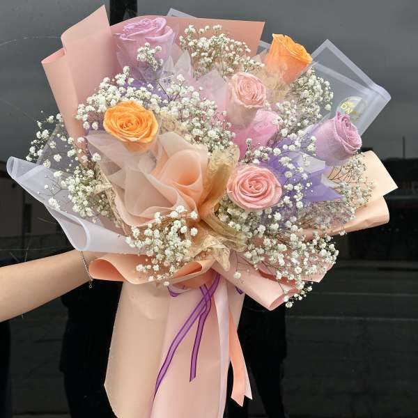 Bouquet of pastel roses and baby's breath wrapped in pink paper