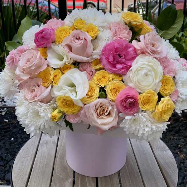 Pink, white, and yellow flowers arranged in a round box