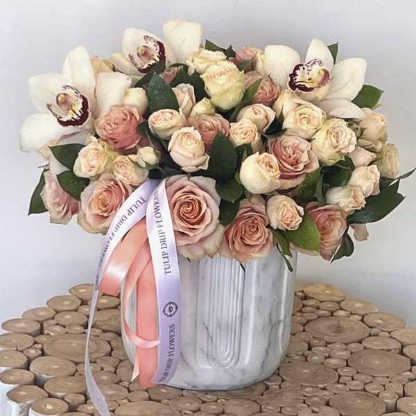 Bouquet of blush roses and white orchids in a white vase