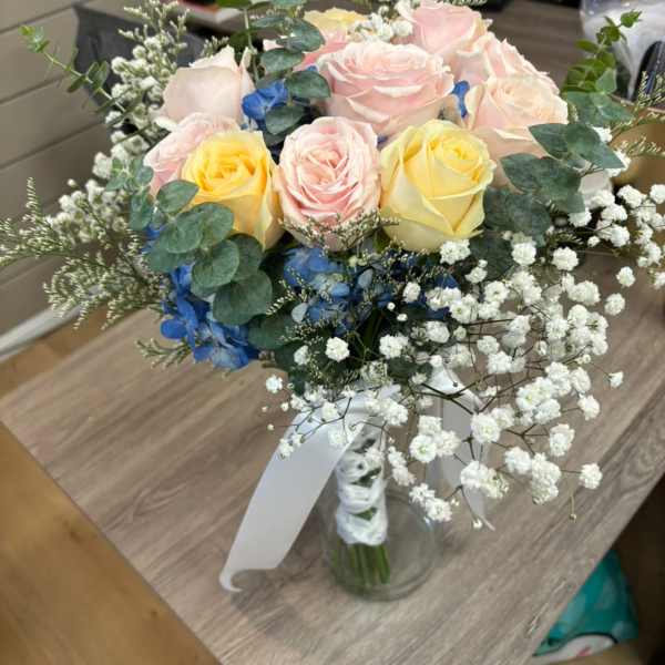 Bouquet of pastel roses with blue flowers in a glass vase