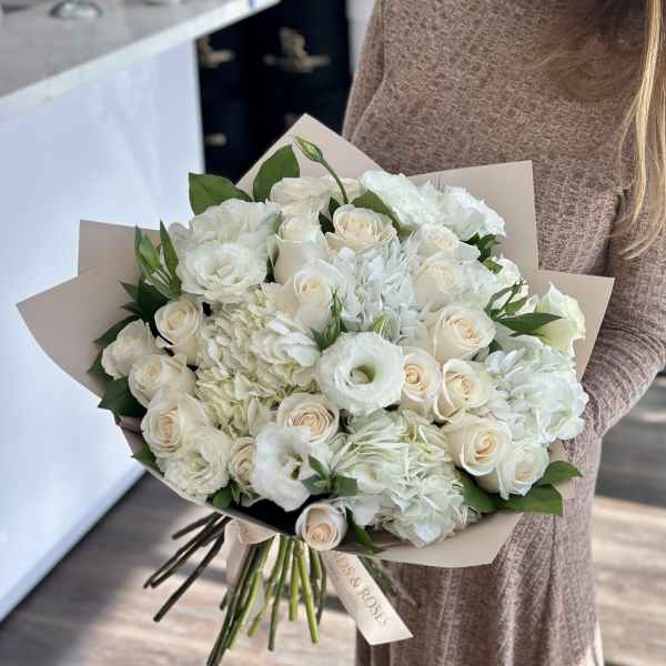 Bouquet of white roses and white hydrangeas wrapped in beige paper