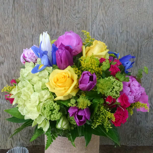 Colorful bouquet in a glass vase wrapped with burlap