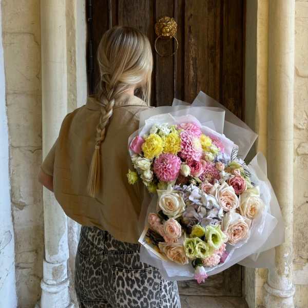 Person holding a large pastel bouquet of mixed flowers