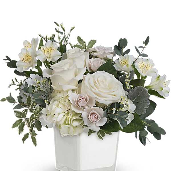 White and blush floral arrangement in a clear square vase