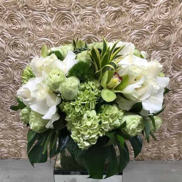 White and pale green floral arrangement in a clear vase