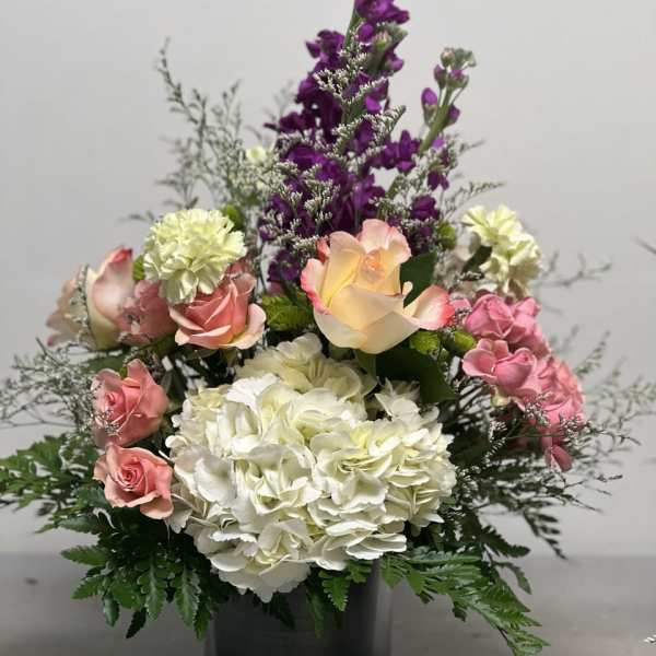 Mixed bouquet of pink, white, and purple flowers in a black vase