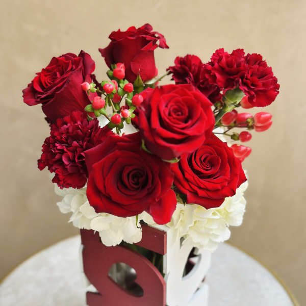 Red roses and carnations arranged in a decorative box