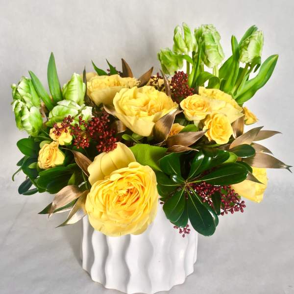 Yellow roses and green tulips in a white vase
