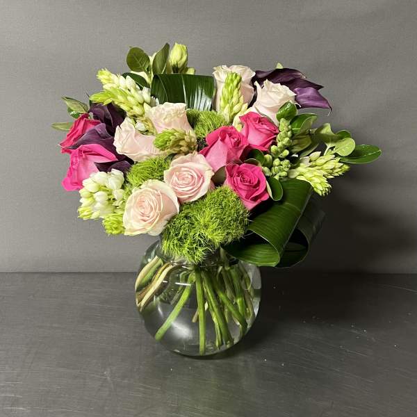 Pink and white roses arranged in a clear glass vase