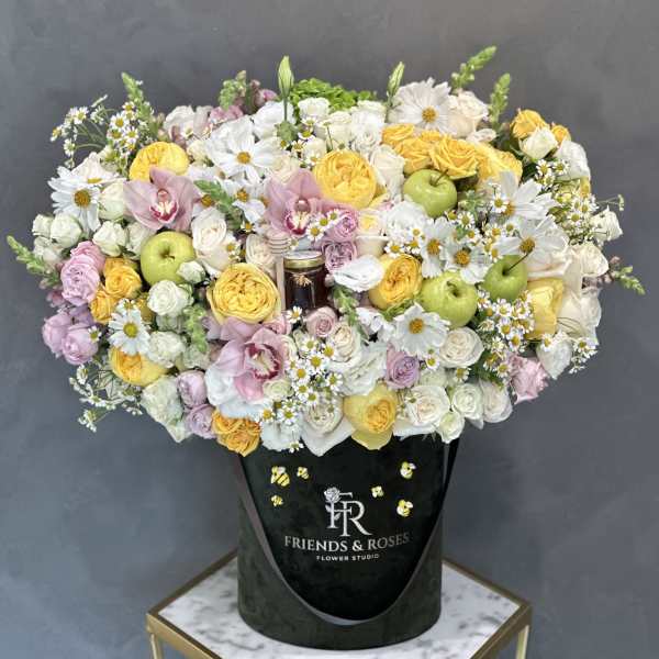 Large mixed bouquet of yellow, white, and pink flowers in a black box