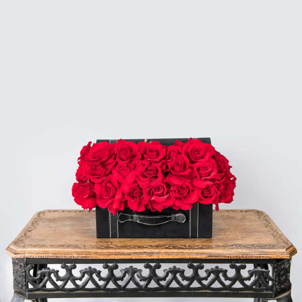 Red roses arranged in a black box on a wooden table
