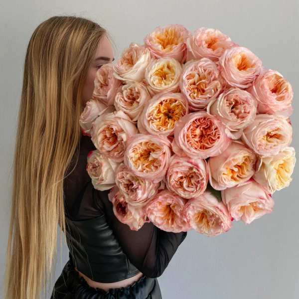Large bouquet of blush and peach roses held by a woman