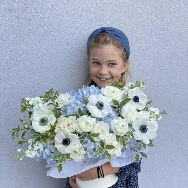 Girl holding a large bouquet of white and pale blue flowers