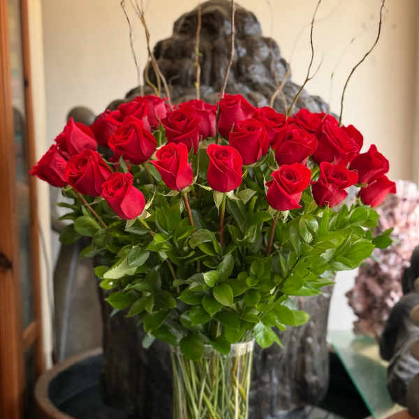 Red roses arranged in a tall glass vase