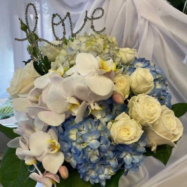 Blue hydrangeas and white roses with white orchids in a bouquet
