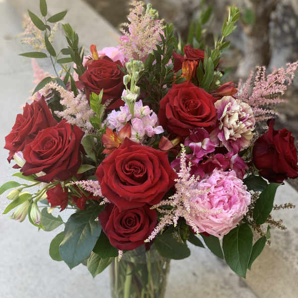 Bouquet of red roses and pink flowers in a clear glass vase
