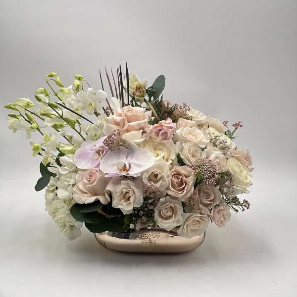 Blush and white floral arrangement in a low metallic vase