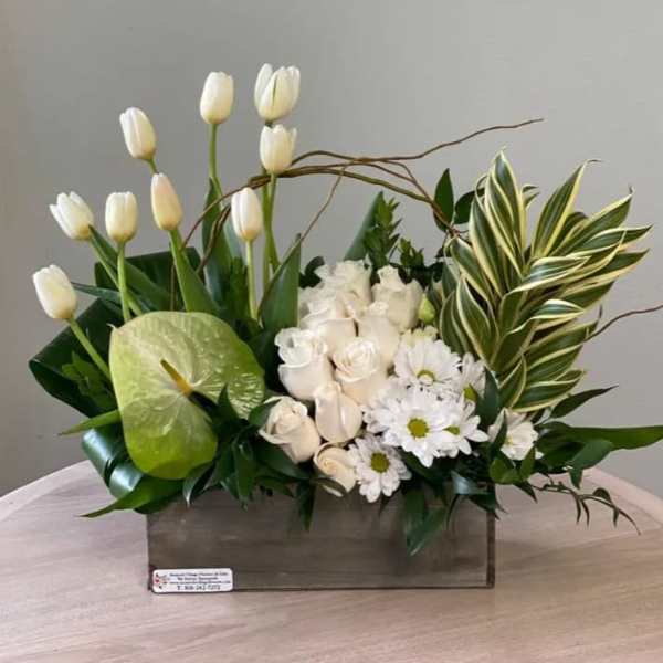 White tulips, roses, and daisies arranged in a wooden box